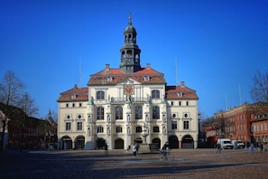 Ein historisches Gebäude mit einem markanten Turm, Bogenfenstern und einer zentralen Turuhr.