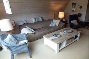 Ein gemütliches Wohnzimmer mit einem braunen Sofa, einem blauen Sessel, einem Holztisch und einer Lampe.