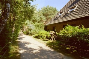 Ein rustikales Gebäude mit geneigtem Dach, einem Weg zum Eingang und einem Vogelhaus im Vordergrund.