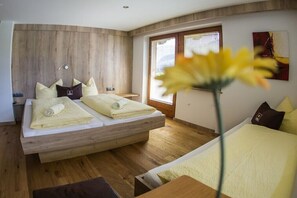 A modern bedroom with a wooden headboard, two beds, a bedside table, a window, and a flower in the foreground. - Apartment in Hippach with swimming pool (Hippach)