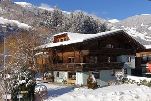 A wooden chalet with a balcony, surrounded by snow-covered mountains. - Apartment in Hippach with swimming pool (Hippach)
