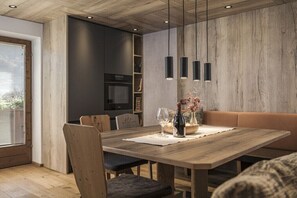 A modern dining area with a wooden table, chairs, pendant lights, and a sofa. - Apartment in Hippach with swimming pool (Hippach)