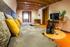 A cozy living room with a sofa, a television, a wine table with bottles, and a view to the outside. - Apartment in Hippach with swimming pool (Hippach)
