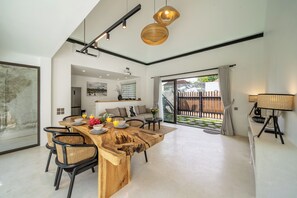 A spacious kitchen with a wooden island, modern pendant lights, and a view to the outdoor area. - Niki Villa Ubud (Ubud)