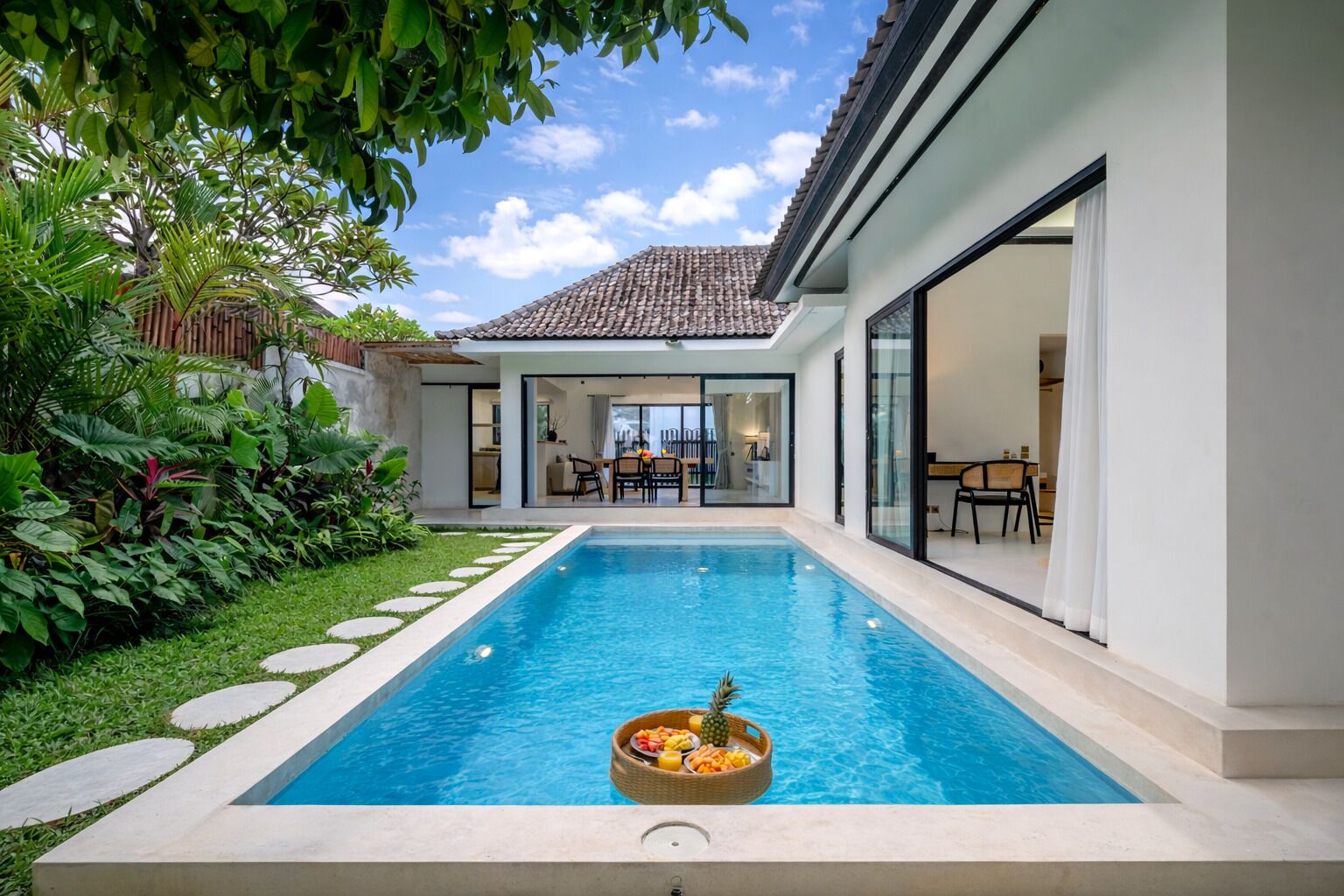 A modern house with a swimming pool, a dining area, and a lush garden.