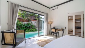 Ein Schlafzimmer mit Bett, Schreibtisch, Stuhl, Kleiderschrank und Blick auf einen Pool.