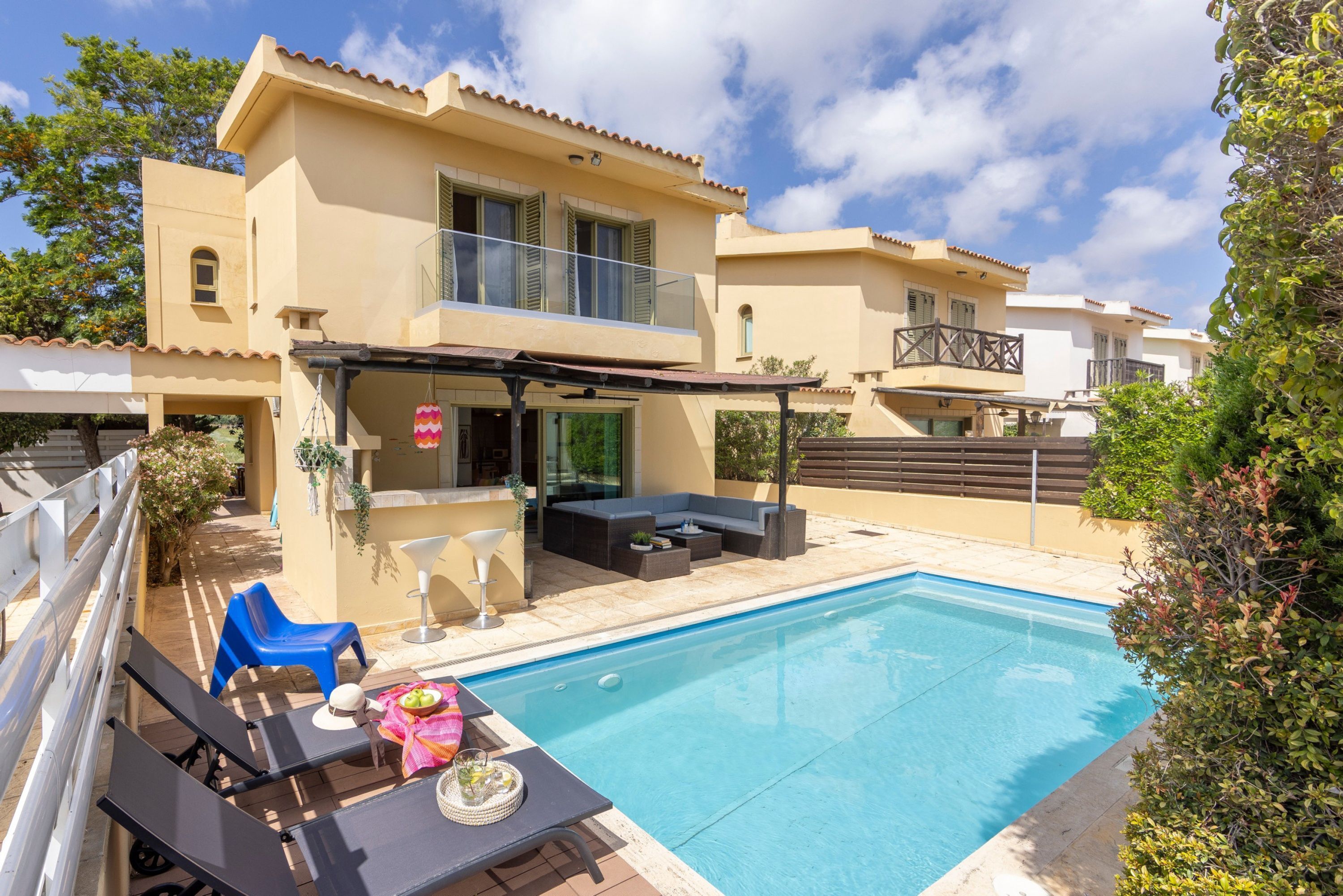 Una casa moderna con piscina, mobiliario exterior y terraza cubierta.