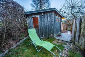 Una cabaña rústica de madera con una sola puerta y un pequeño porche.