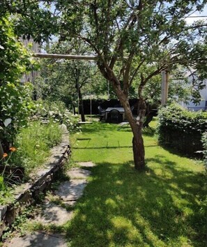 A garden with a lawn, a tree, and a stone wall. - Holiday home with 4 bedrooms (Burg Reuland)