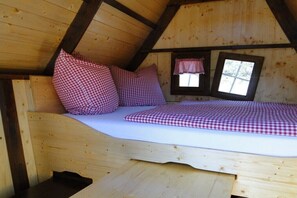 A wooden cabin bedroom with a bed, pillows, and a window. - Serviceberry in the heathland magic (Bispingen)