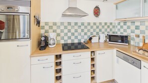 A modern kitchen with a built-in oven, coffee maker, microwave, and a toaster.