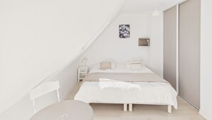 A minimalist bedroom with a bed, bedside table, lamp, and a small picture on the wall.
