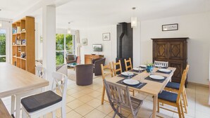 A dining area with a long table, chairs, and a television.