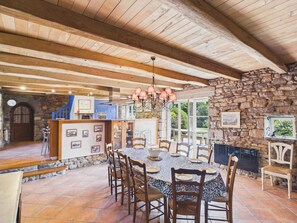 A dining area with a stone wall, wooden ceiling beams, and a tiled floor. - Authentic house for 11, close to the beach (Landéda)