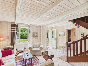 A spacious living room with a high ceiling, a fireplace, a dining area, and a staircase leading to another level. - Authentic house for 11, close to the beach (Landéda)