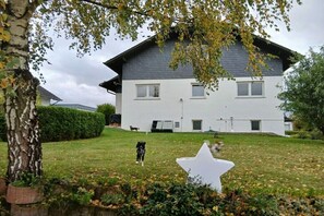 A two-story house with a white exterior and dark roof, surrounded by a well-maintained lawn and a large white star decoration. - Holiday apartment with 1 bedroom (Altenkirchen Lahn-Dill-Kreis)