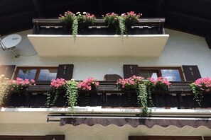 A building with two balconies, each adorned with flower boxes and climbing plants. - Country House Alpine Treasure (Reit im Winkl)