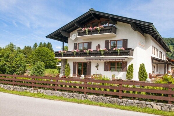 A two-story building with balconies, a stone foundation, and a wooden fence. - Country House Alpine Treasure (Reit im Winkl)