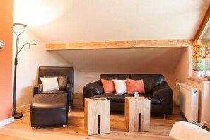 A loft-style living room with a black leather sofa, a matching ottoman, and two wooden side tables. - Country House Alpine Treasure (Reit im Winkl)