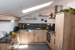 A modern kitchen with wooden cabinets, a black tiled backsplash, and a skylight. - Country House Alpine Treasure (Reit im Winkl)