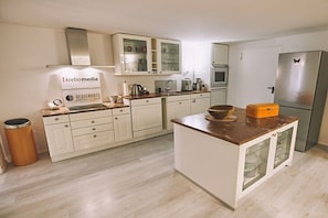 Eine moderne Küche mit weißen Schränken, einer zentralen Kochinsel und einem Edelstahl-Kühlschrank.
