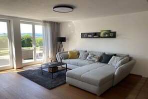 Ein Wohnzimmer mit einer Couch, einem Couchtisch, einer Stehlampe und einem Wandregal mit Dekoration.
