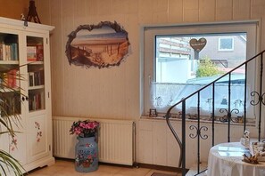 Ein Zimmer mit Bücherregal, Wanddeko, Fenster mit Aussicht und einer Treppe.