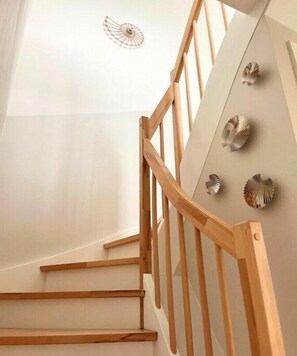 Eine Holztreppe mit weißer Wand und dekorativen Muscheln.