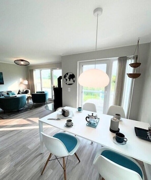 Ein moderner Essbereich mit einem weißen Tisch, blauen Stühlen und einem großen Fenster.