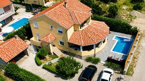 A multi-story building with a swimming pool, a covered patio, and a parking area. - Kakma Apartment private pool (Kakma)