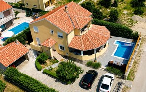 A multi-story building with a swimming pool, a covered patio, and a parking area. - Kakma Apartment private pool (Kakma)