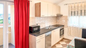 A compact kitchen with a microwave, stove, sink, and a dishwasher. - Kakma Apartment private pool (Kakma)
