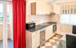 A compact kitchen with a microwave, stove, sink, and a dishwasher. - Kakma Apartment private pool (Kakma)