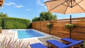 A swimming pool with lounge chairs and an umbrella. - Kakma Apartment private pool (Kakma)