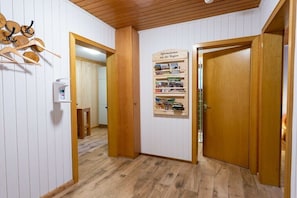 A hallway with wooden flooring, a wooden door, a mirror, and a bulletin board with regional information. - Holiday home with 2 bedrooms (Böddenstedt)
