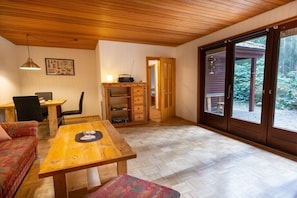 A wooden interior with a dining table, sofa, and a sliding glass door leading to an outdoor area. - Holiday home with 2 bedrooms (Böddenstedt)
