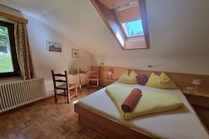 A bedroom with a bed, a desk, a chair, a radiator, and a skylight.