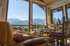 Ein Zimmer mit großen Fenstern, Holzmöbeln und Bergblick.