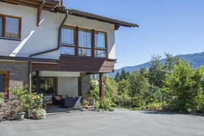 Ein zweistöckiges Gebäude mit Balkon, Steinfassade und Bergblick.
