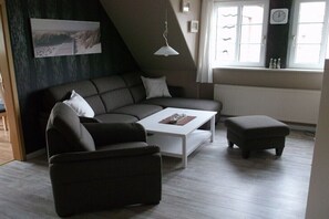 Ein modernes Wohnzimmer mit einer Eckcouch, einem weißen Couchtisch und einem kleinen Hocker.