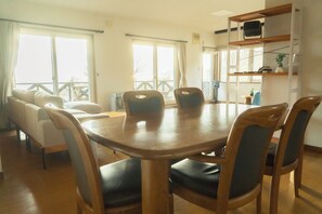 Un coin repas avec une table et des chaises en bois, un canapé et un balcon doté d’une balustrade.