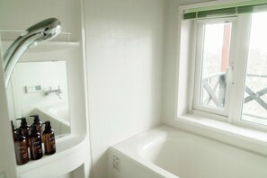 Une salle de bain avec une baignoire, une fenêtre et un miroir.