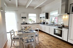 Eine moderne Küche mit weißen Schränken, Holzboden und einem Essbereich mit Frühstückstisch.
