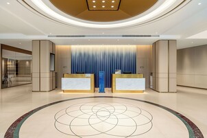 Un área de recepción moderna con dos mostradores, una pared de acento azul y un diseño de piso circular.