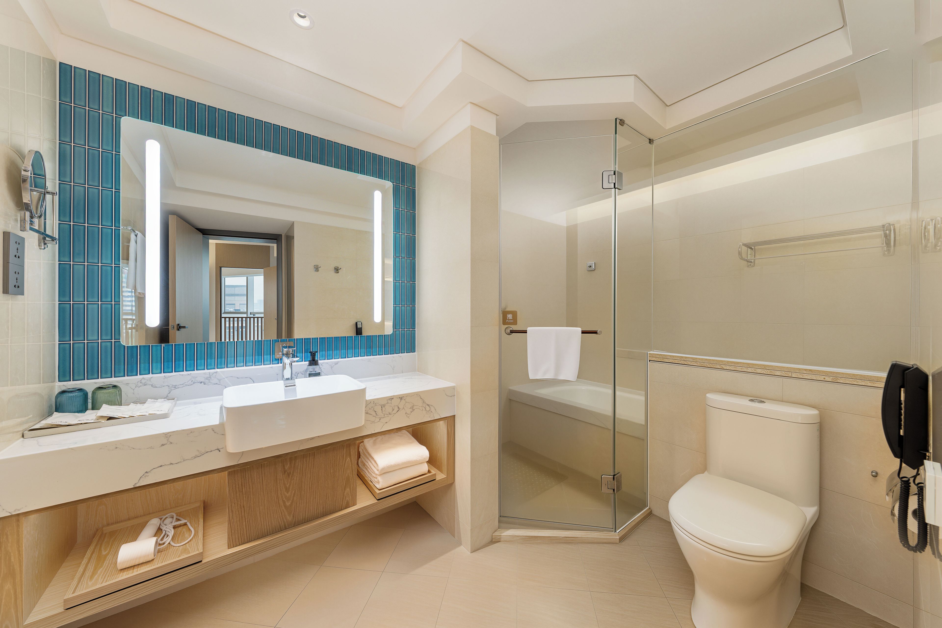 Une salle de bain moderne avec un grand miroir, une douche à parois de verre et des toilettes.