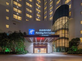 Entrada de un hotel Holiday Inn Express con diseño moderno, destacando una señalización llamativa, fachada de vidrio y un área de acceso bien iluminada.