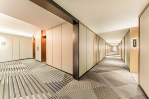 Un pasillo de hotel con alfombra estampada, paneles de madera y un cartel que indica la habitación 811.