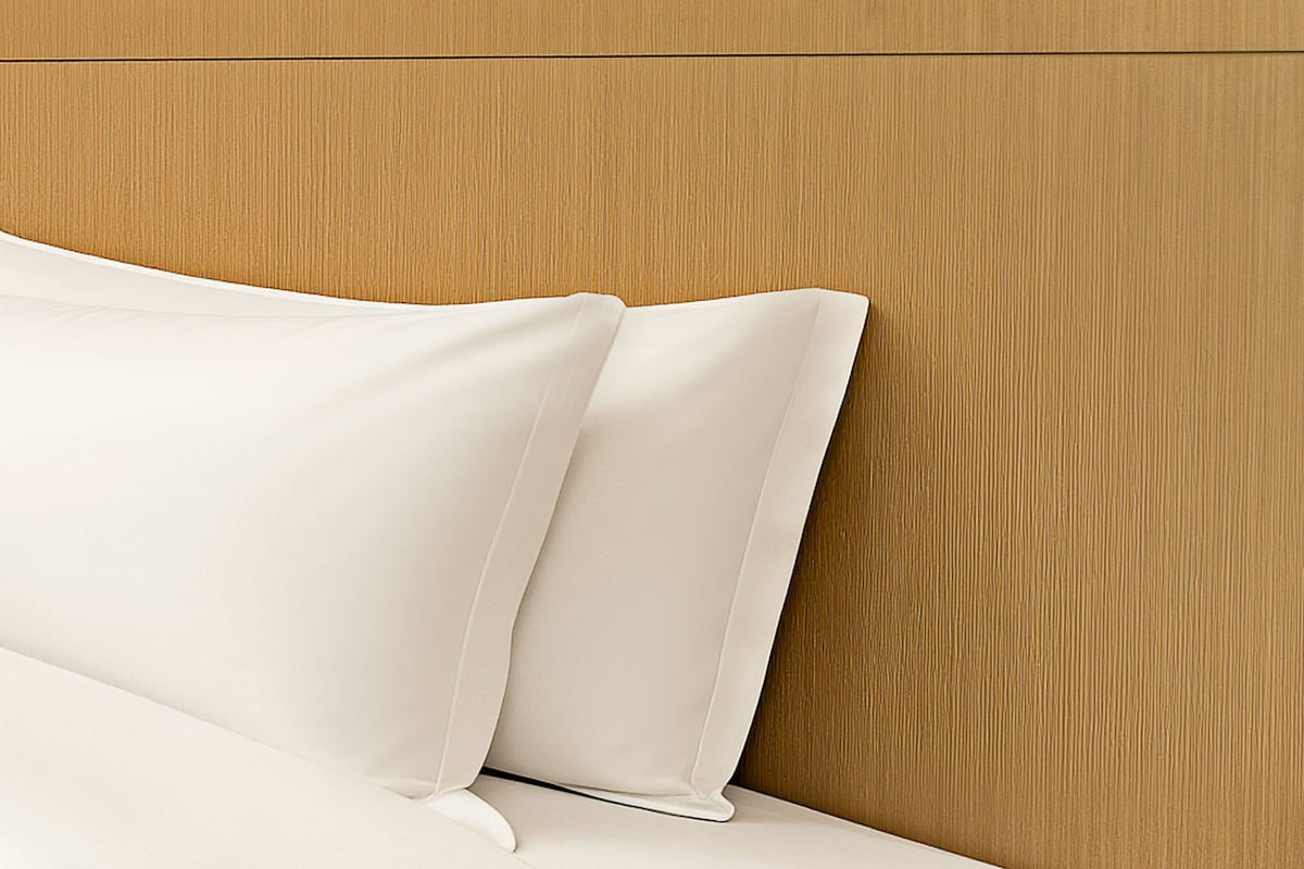 Una cama con ropa blanca y un cabecero de madera.