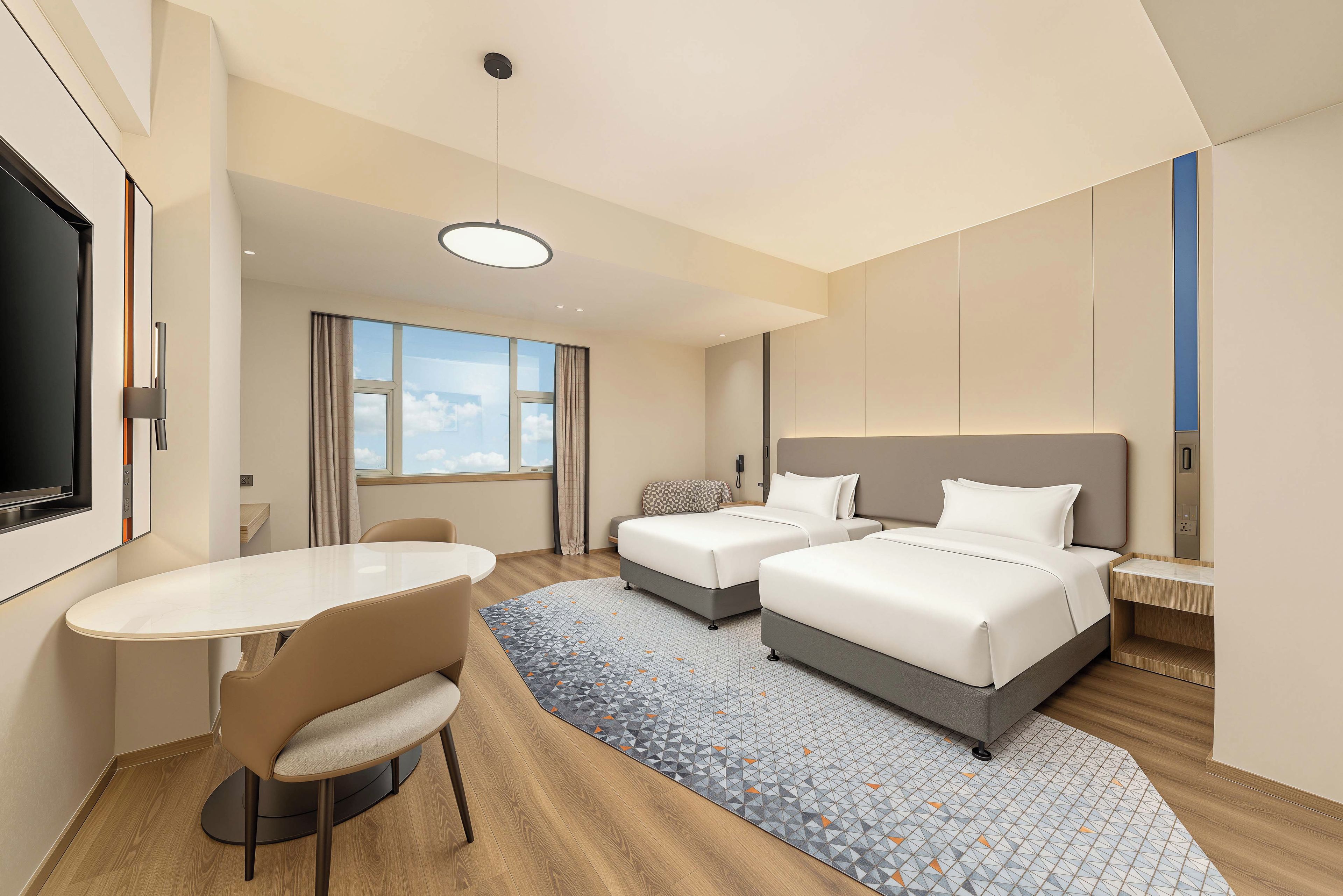 Quarto de hotel com duas camas, uma escrivaninha e uma cadeira.