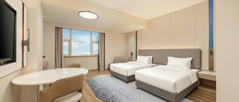 Quarto de hotel com duas camas, uma escrivaninha e uma cadeira.
